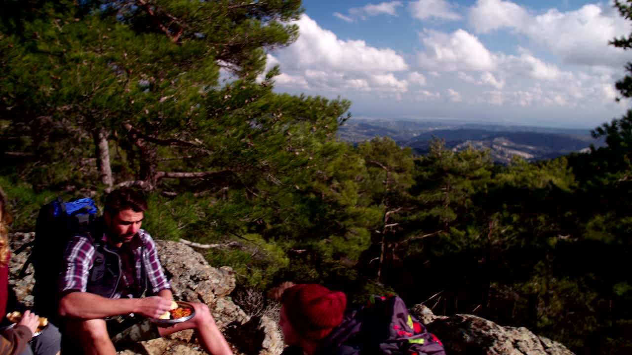 Couples hiking on the mountain having a picnic and resting