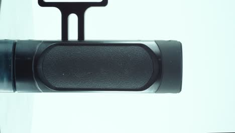 un primer plano vertical de un controlador de cámara de metal negro, equipo de producción de video, en un soporte giratorio de 360, iluminación de estudio, cámara lenta, 4k