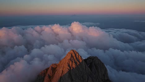 mountain peak above the clouds at sunrise/sunset