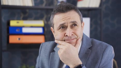 Thoughtful-businessman-working-on-laptop-in-office.