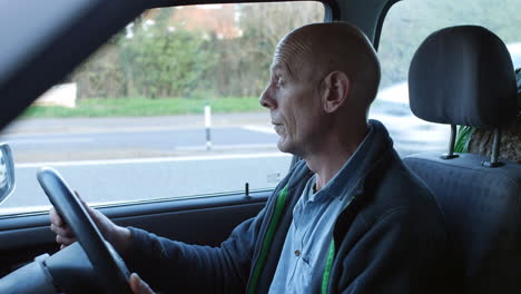 a tired man falling alseep in a car on a busy road in a traffic jam