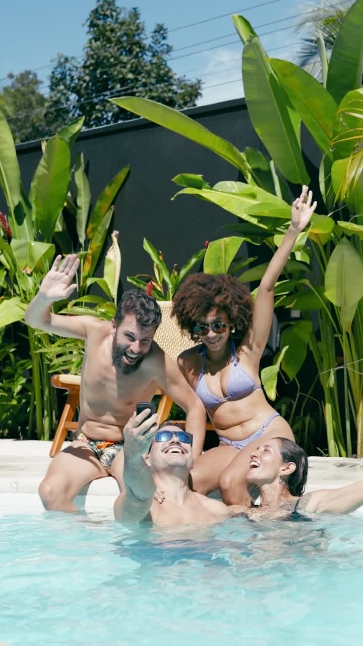 Amici felici che si scattano un selfie in una piscina tropicale.