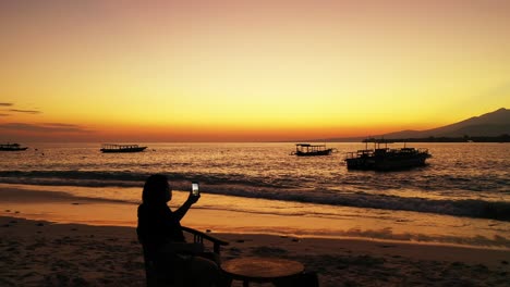 Eine-Frau,-Die-Nahe-Am-Ufer-Sitzt-Und-Panoramavideos-Des-Wunderschönen-Horizonts-Von-Phuket-Aus-Der-Ferne-Macht-–-Totalaufnahme