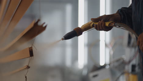 A-close-up-of-Molar-sprays-paint-on-steel-profiles-in-a-respirator-mask-and-protective-suit-in-slow-motion.-Production-and-painting-studio.-Powder-coating