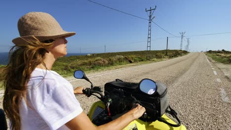 Beautiful-woman-wearing-a-hat-driving-an-ATV-on-the-island-,-summer-time