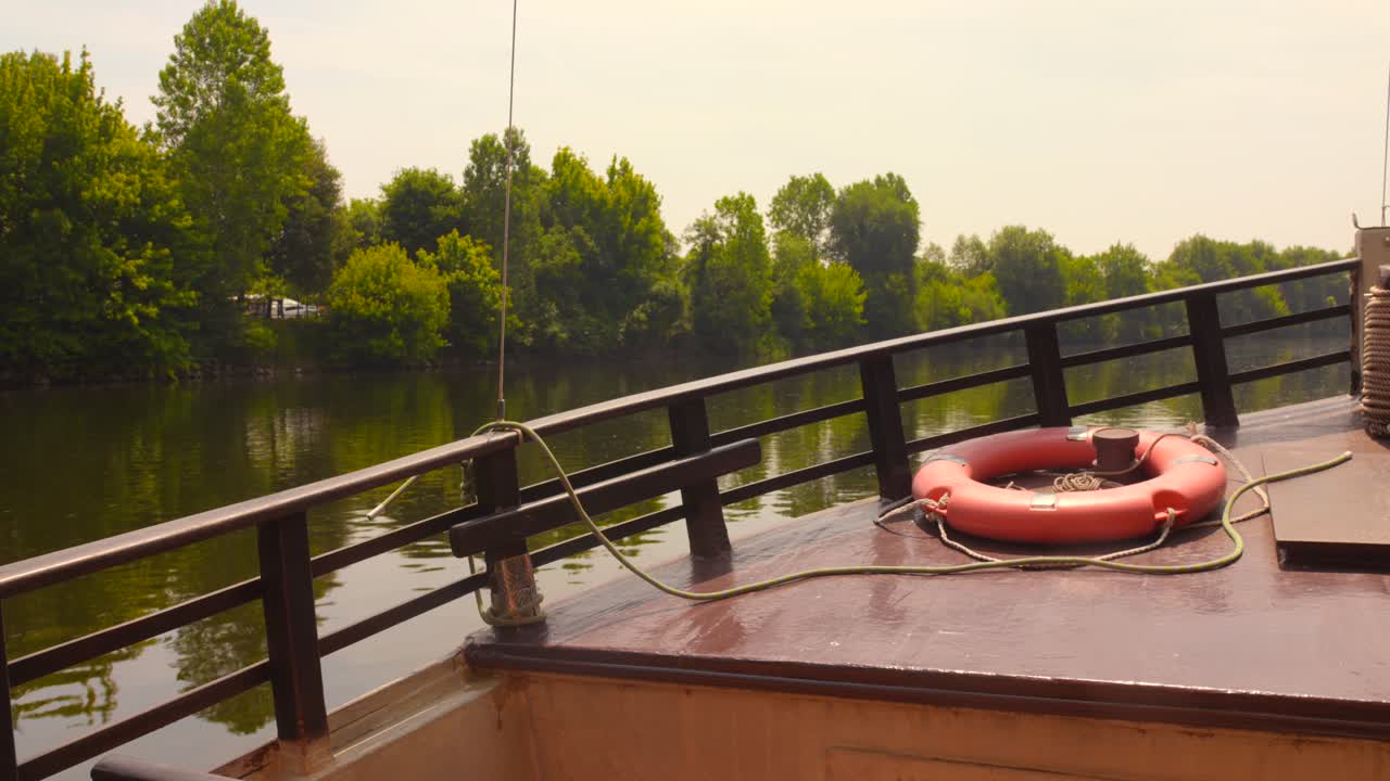 Sailing through Dordogne river on a traditional boat in France with lush, dense banks . 4k