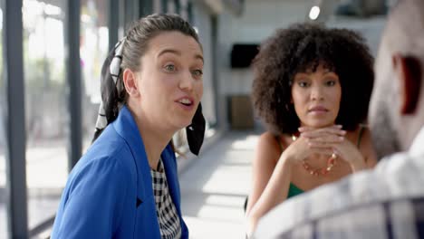 three diverse colleagues discussing while sitting on a table together at office