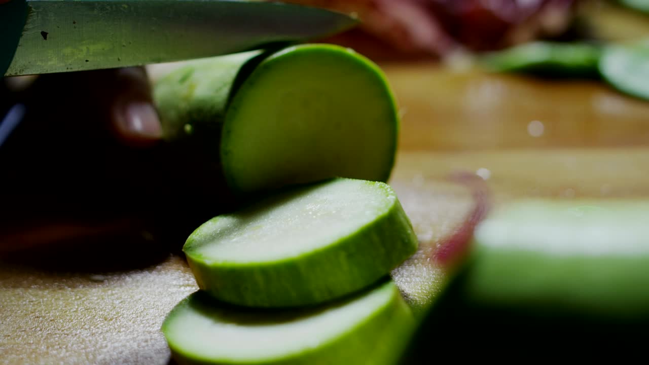 macro en cámara lenta de un chef de mediana edad cortando calabazas con un cuchillo en una tabla de madera