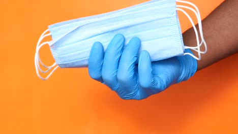 hand holding multiple folded medical masks and blue nitrile gloves