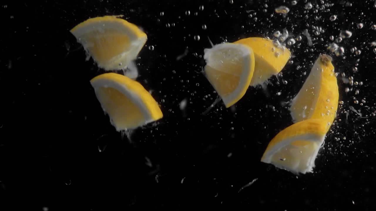 Lemon Pieces Falling into Water Super Slowmotion, Black Background, lots of Air Bubbles, 4k240fps