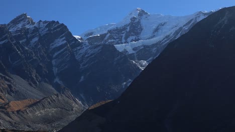 Zoom-out-view-of-Himalayan-peaks,-snowy-Himalayan-mountains,-tent-pitched-for-mountaineers-to-stay---relax