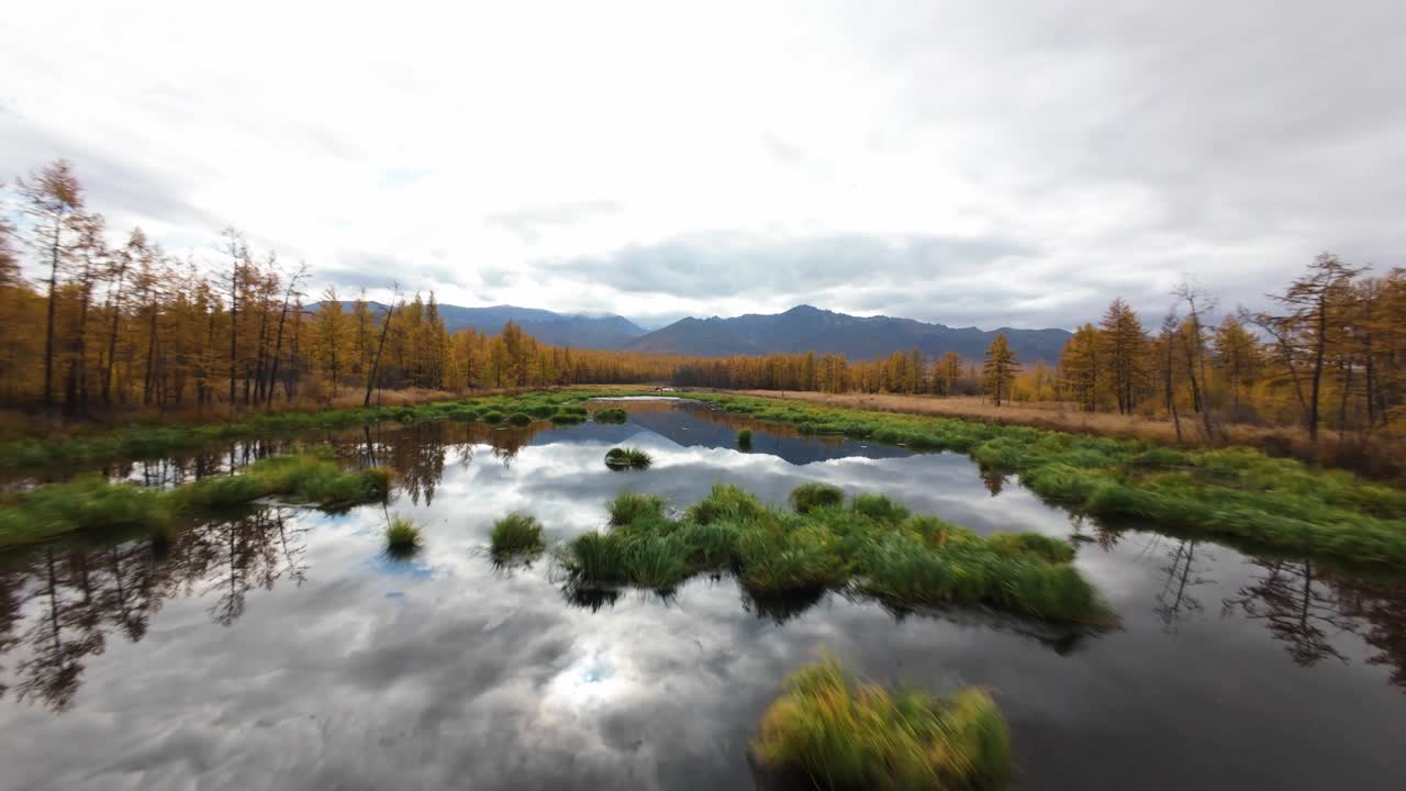 Experience the breathtaking beauty of a still mountain lake reflecting vibrant autumn foliage under a cloudy sky. Nature's colors merge in perfect harmony, creating a tranquil escape.