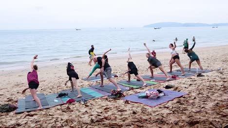 group practicing yoga on a sandy beach