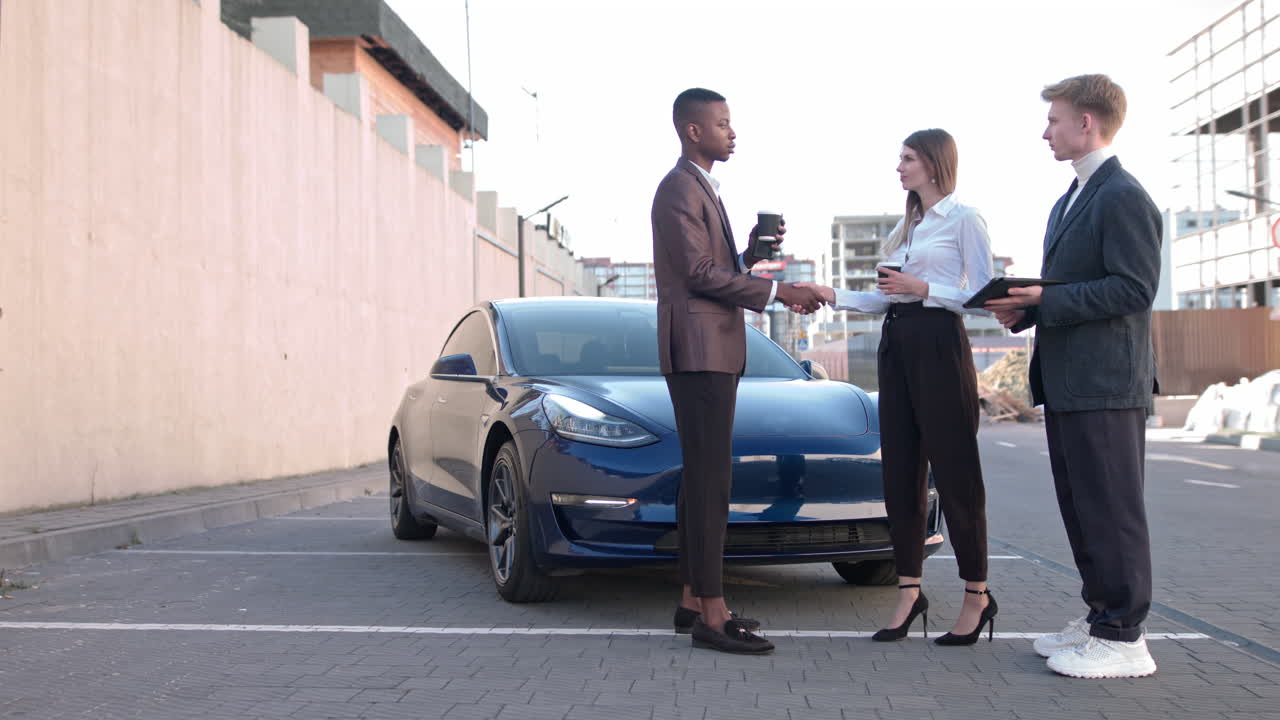 Un affascinante uomo afroamericano e una splendida donna europea in abiti formali parlano con un concessionario auto