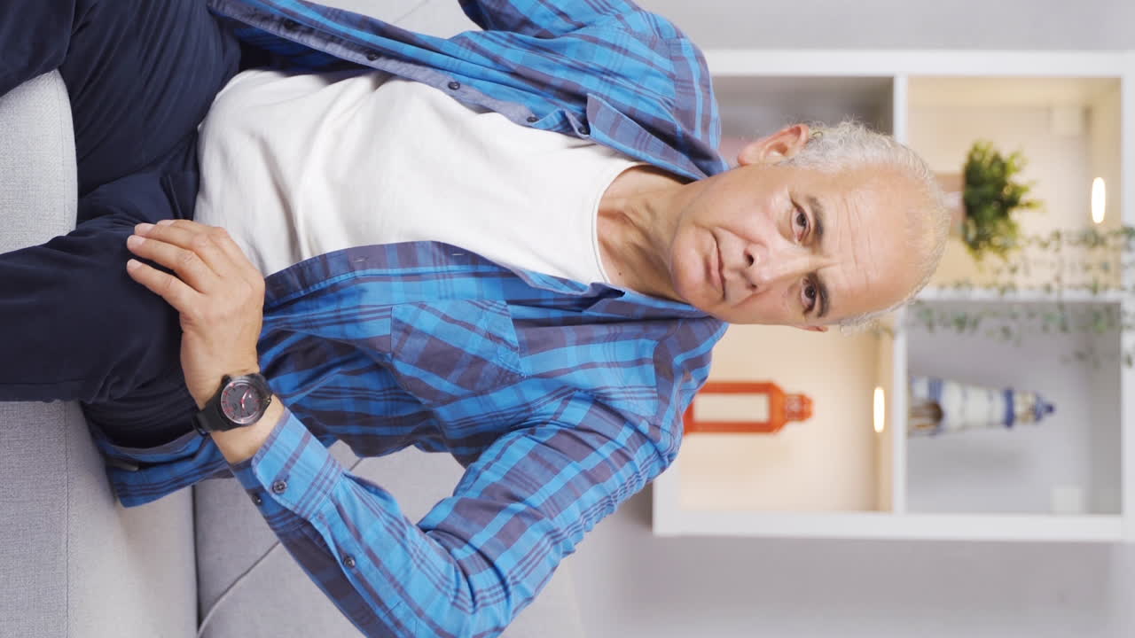 Vertical video of Elderly man looking at camera with negative expression.