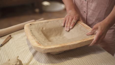 a close-up of female potters hands shaping clay plate. ceramic handmade product. artist working in workshop.