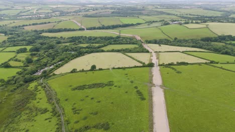 Aerial-view-of-new-infrastructure-being-excavated-through-UK-countryside,-featuring-fields-and-construction-activity