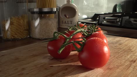 Tomates-Besados-Por-El-Rocío-Sobre-Una-Tabla-De-Cortar-De-Madera,-Iluminada-Por-El-Sol-Por-La-Mañana