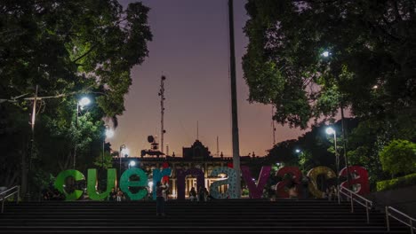 stabilized shot of cuernavaca tourist sign in mexico during sunset, movement of cars, people and lights.