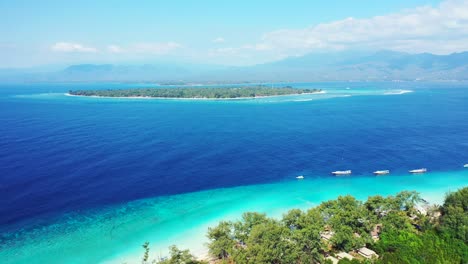 Insel-In-Indonesien-–-Tropisches-Paradies-Aus-Grünen-Bäumen-Und-Weißem-Sand,-Umgeben-Von-Tiefblauem-Meerwasser-Mit-Booten-In-Ufernähe-–-Weitwinkelaufnahme