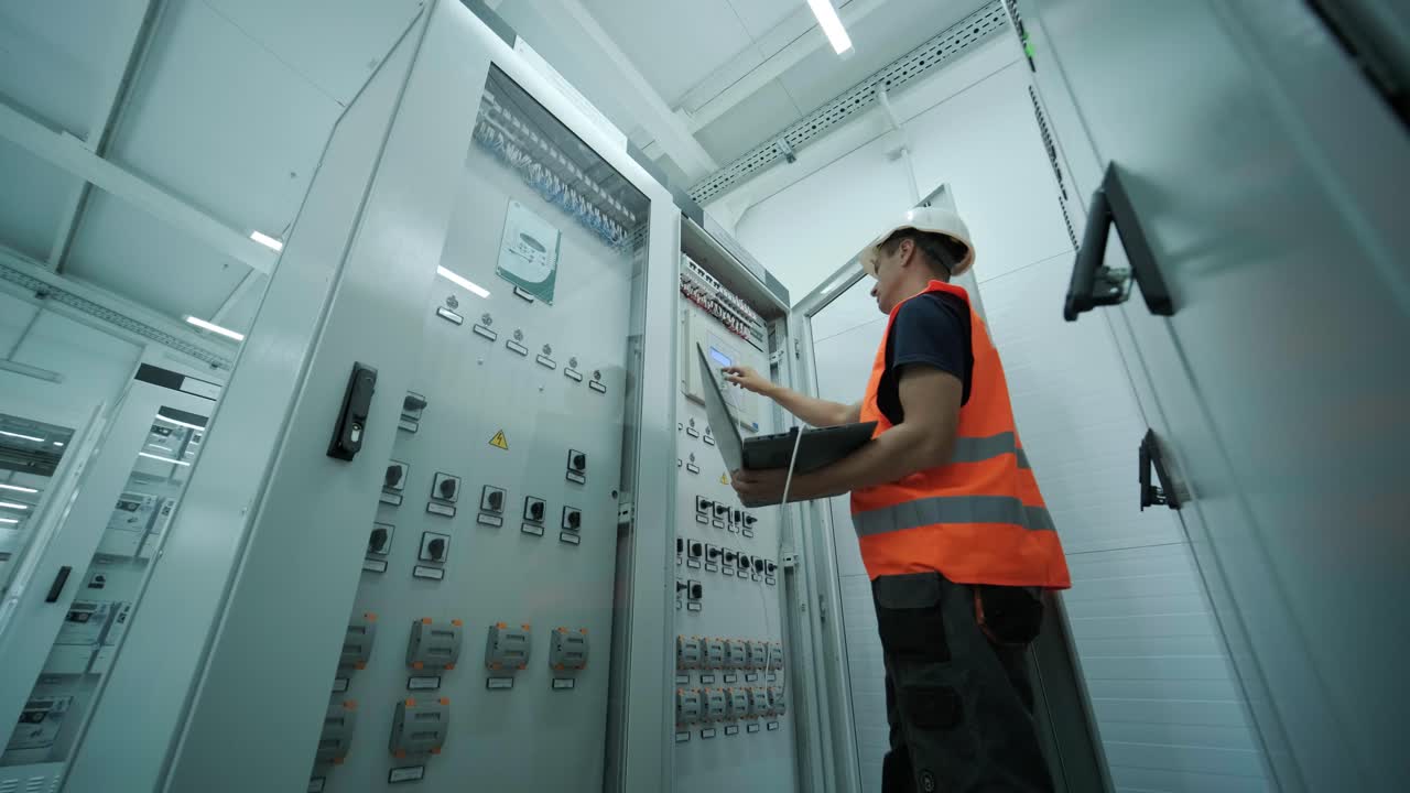 el ingeniero eléctrico que trabaja comprueba la tensión de corriente eléctrica y la sobrecarga en la parte delantera del gabinete del centro de carga o de la unidad de consumo para el mantenimiento en la sala principal del sistema de distribución de energía.