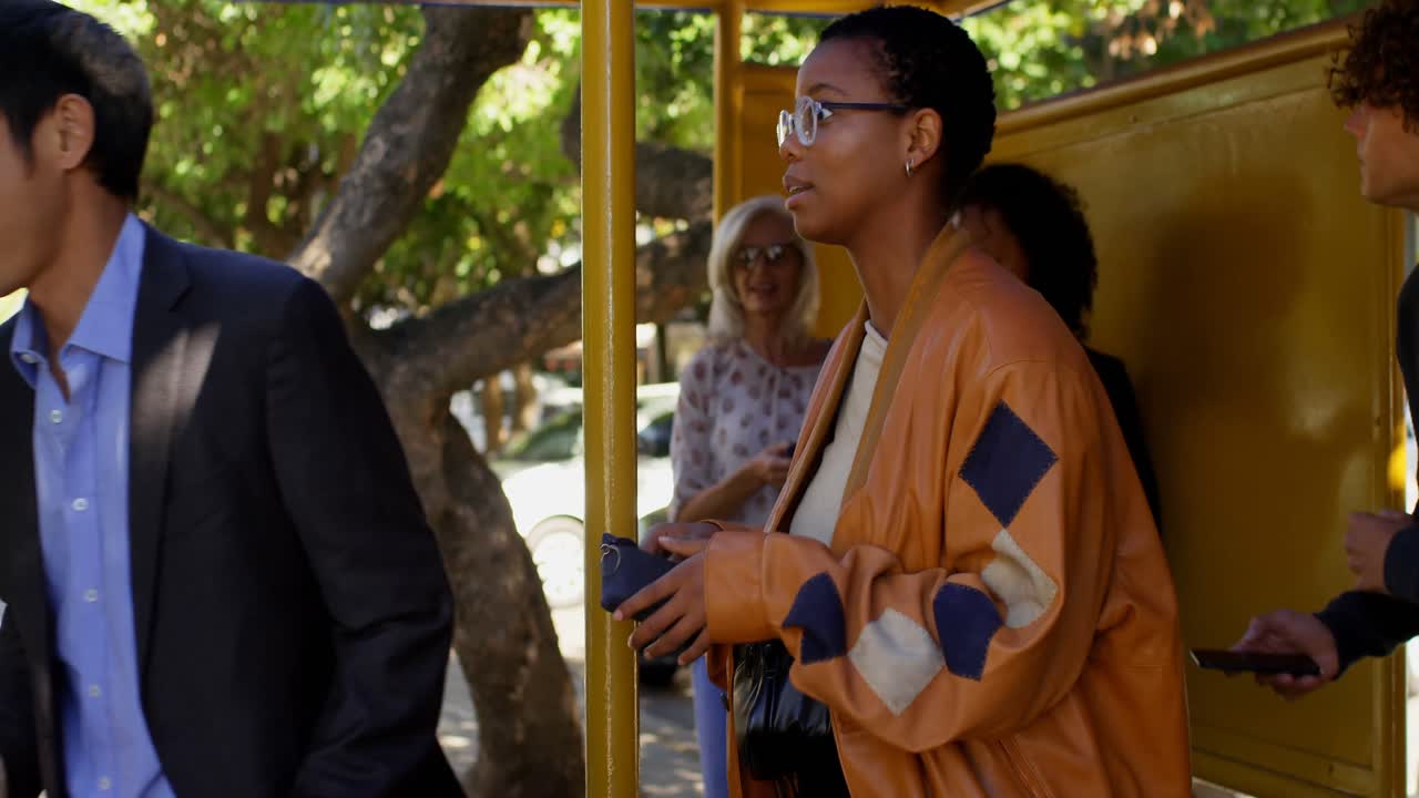 pasajeros que usan teléfonos móviles en la parada de autobús 4k