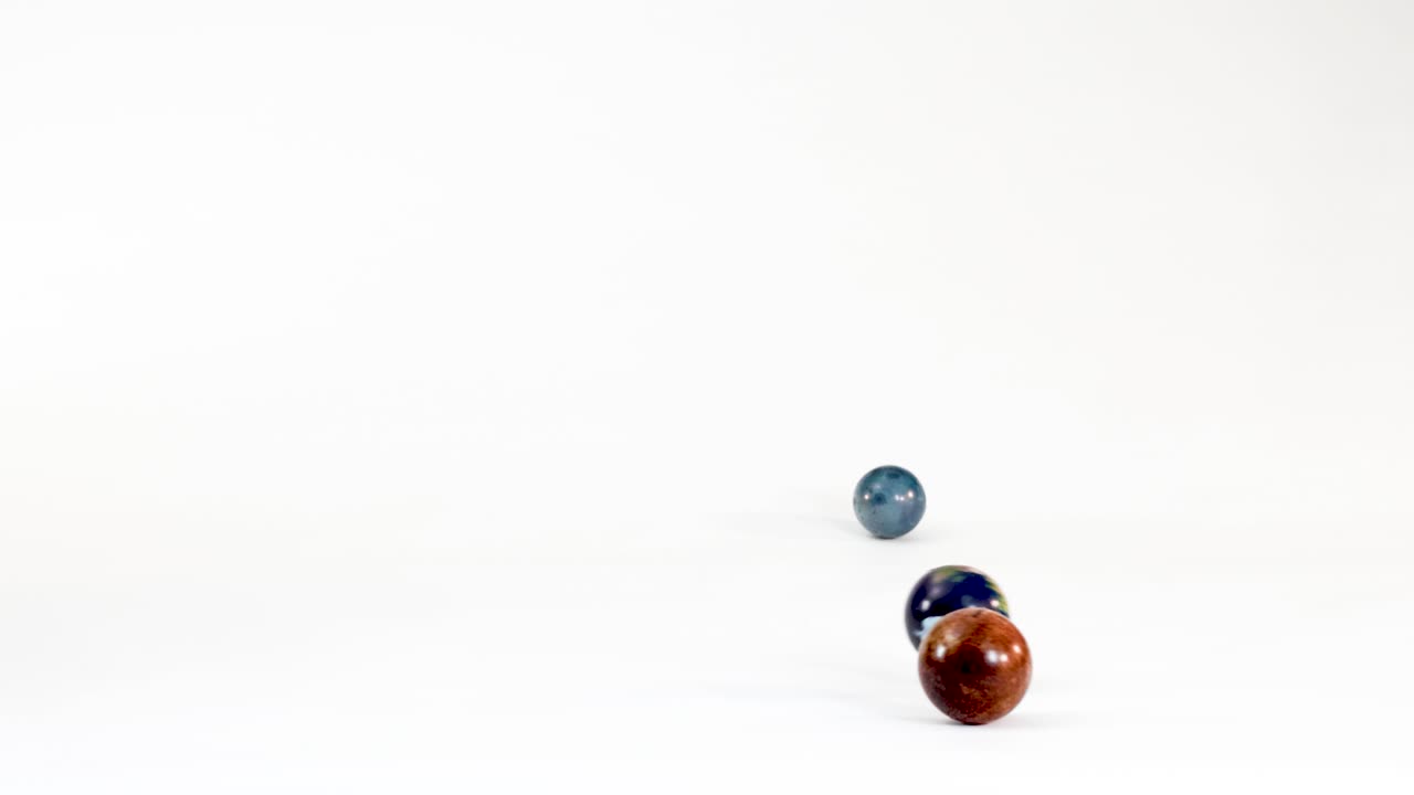 Small colorful marbles and an Earth planet ball bounce across a bright white studio background