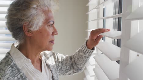 Afroamerikanische-ältere-Frau,-Die-Zu-Hause-Aus-Dem-Fenster-Schaut