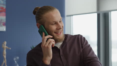 Relaxed-man-chatting-smartphone-at-office-portrait.-Smiling-freelancer-resting