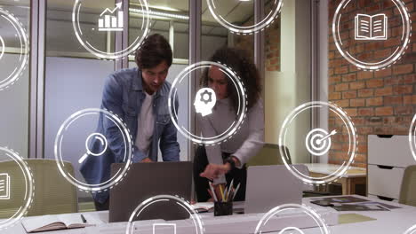 Animation of multiple digital icons against diverse man and woman shaking hands at office