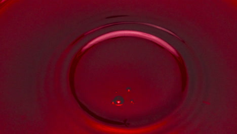 circle shaped wine drops falling into glass closeup.