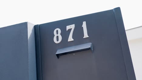 dark gate with silver 871 house number mounted on it under bright daylight