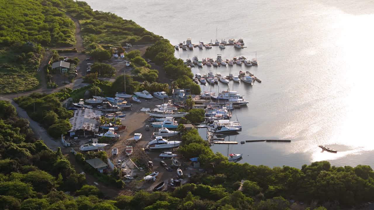 la luz del amanecer brilla en las aguas del caribe en el puerto de piscadera, barcos de pesca y yates atracados