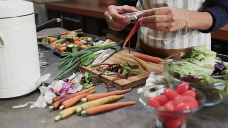 Hands-of-biracial-woman-peeling-vegetables-in-kitchen,-slow-motion