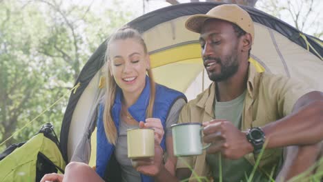 happy diverse couple camping and drinking tea in park, slow motion