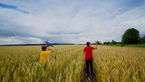 boys running with plane toy. boys running with toy plane on golden wheat field