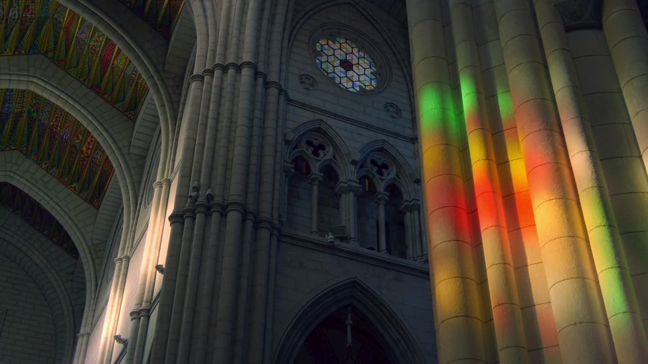 sunlight falls trough stained glass inside la almudena cathedral in madrid. fast camera movement