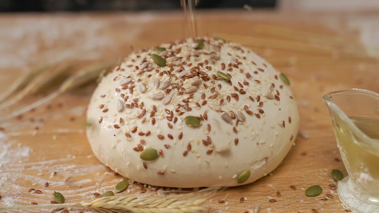 Sprinkling Various Seeds on Fresh Bread Dough