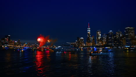 beautiful night skyline of modern new york, usa with fireworks flashes. numerous boats are watching the show on the river