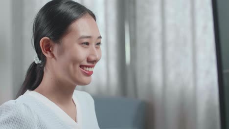 집에서 데스크에서 작업하는 동안 카메라에 미소 짓는 하우스 모델과 함께 아시아 여성 엔지니어의 클로즈업