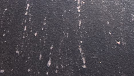 Ocean Foam Patterns on Dark Sand Beach