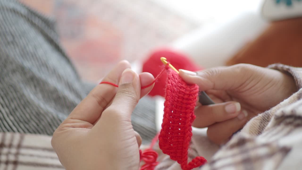 Close-up of a person crocheting with red yarn