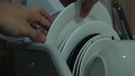 a white plate being placed in kitchen dishrack after washing. -static close-up shot