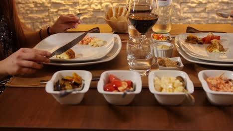 churrascaria - girl eating scamorza cheese, revealing another girl with a pan at a brazilian fine restaurant with red wine and vegetables - uhd