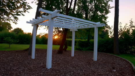 white pergola at sunset in a garden landscape