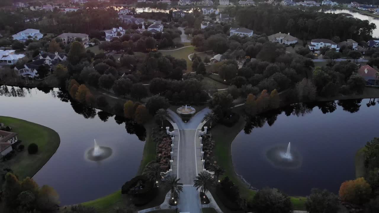 태양이 지는 동안 두꺼운 개발되지 않은 숲으로 둘러싸인 고립된 럭셔리 북 플로리다 동네로 이어지는 다리의 공중