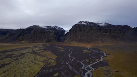 Montañas-Islandesas-Con-Glaciar-Derritiéndose-Creando-Un-Río-Trenzado---Avance-Aéreo