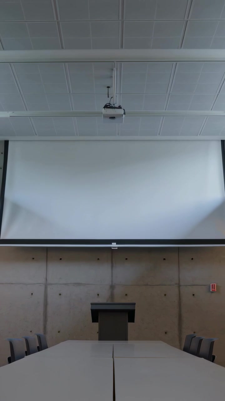 Vertikal video: Motorisert skjerm heves, avslører talerstol og vegg i styrerom, viser projektor