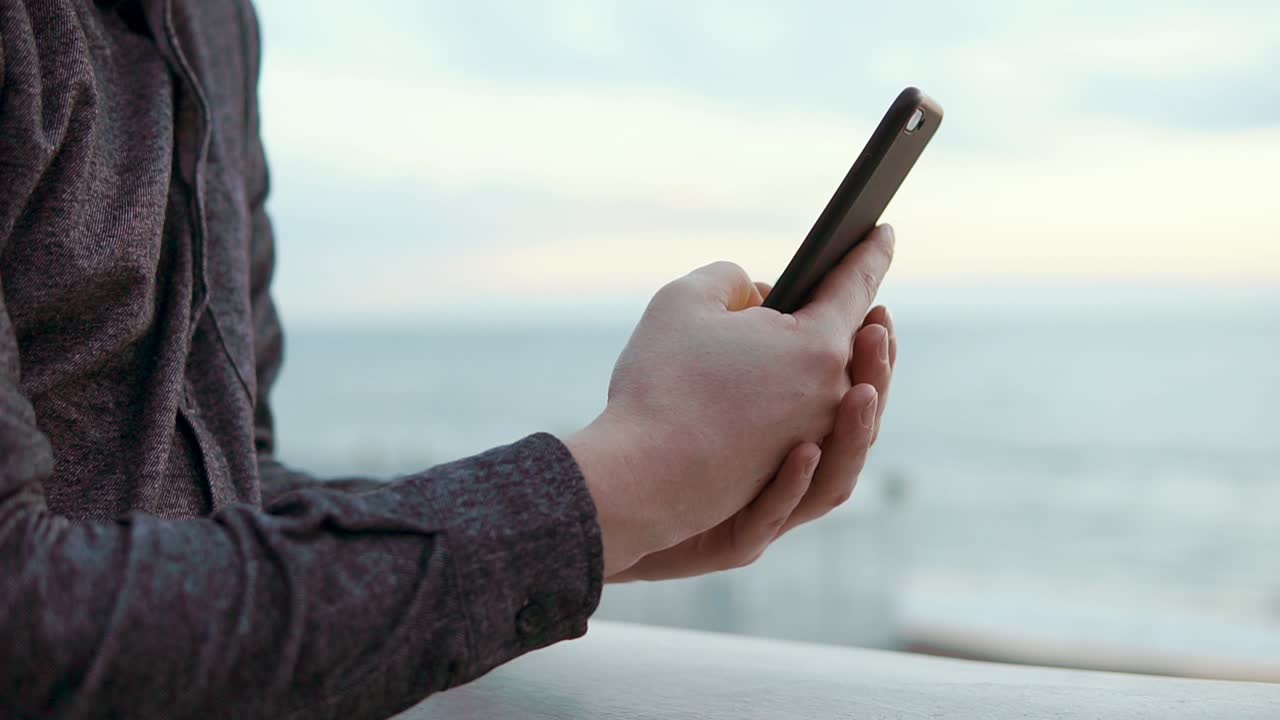 Uomo che usa lo smartphone in riva al mare