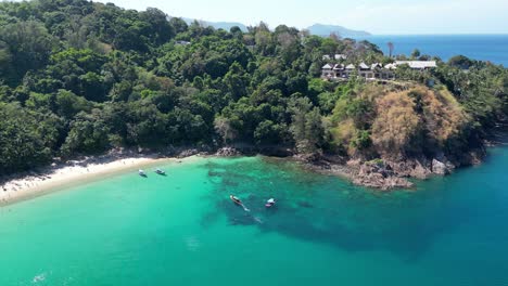 aerial view of hidden beach and turquoise cove on phi phi don (thailand), with boats and lush jungle hillside villas